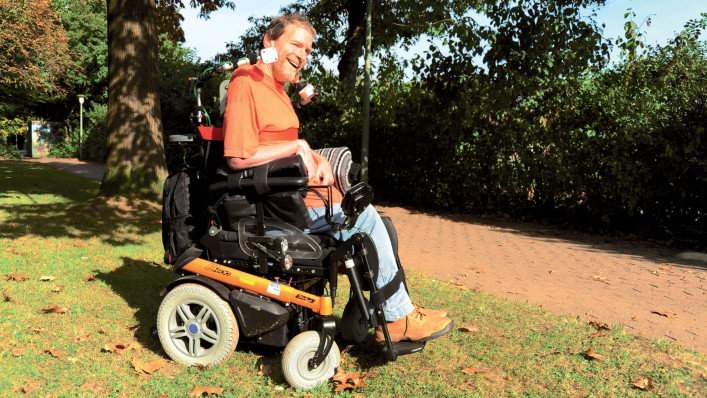 Un homme en fauteuil roulant, en promenade dans un parc